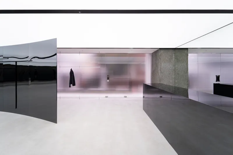 Translucent glass wall and dark metal display surfaces beneath an angular white ceiling plane