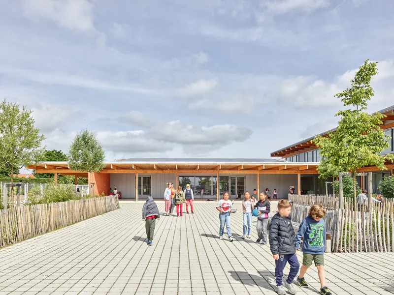 Timber boardwalk courtyard with bamboo fencing and children walking under cloudy afternoon light