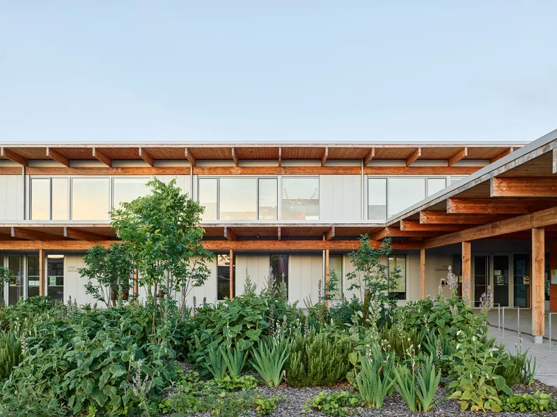 Central courtyard garden with dense plantings framed by timber beams and white-paneled facade wings