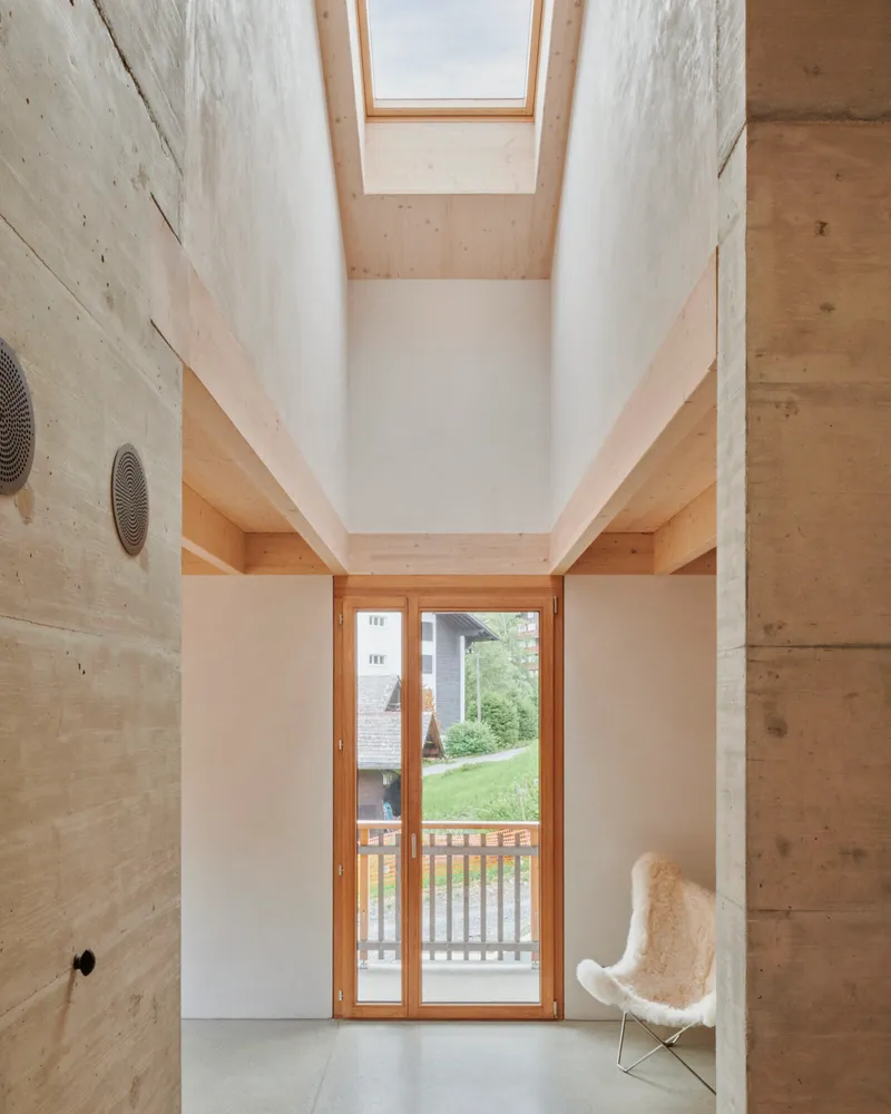 Double-height space with skylight above timber balcony and glazed doors opening to garden