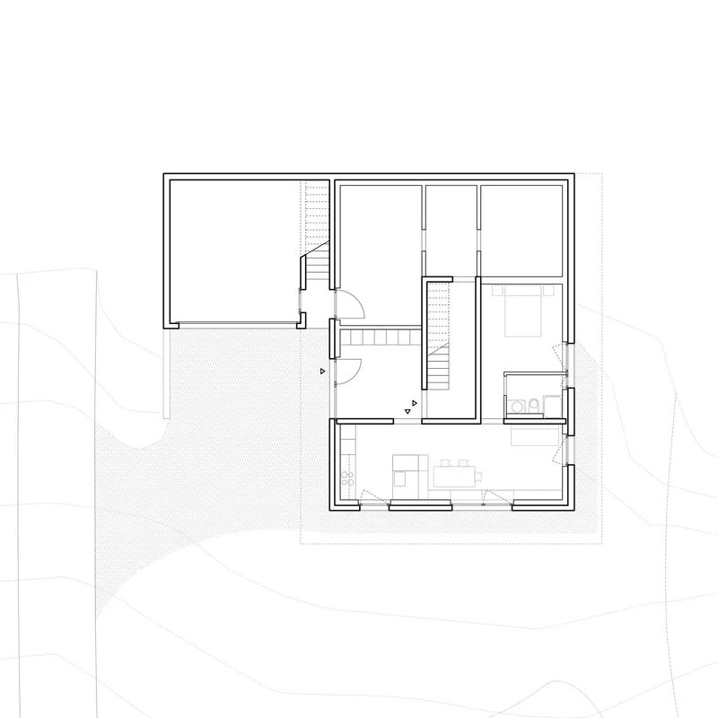 Floor plan drawing showing a rectangular volume with central staircase, bedroom, bathroom and open living space