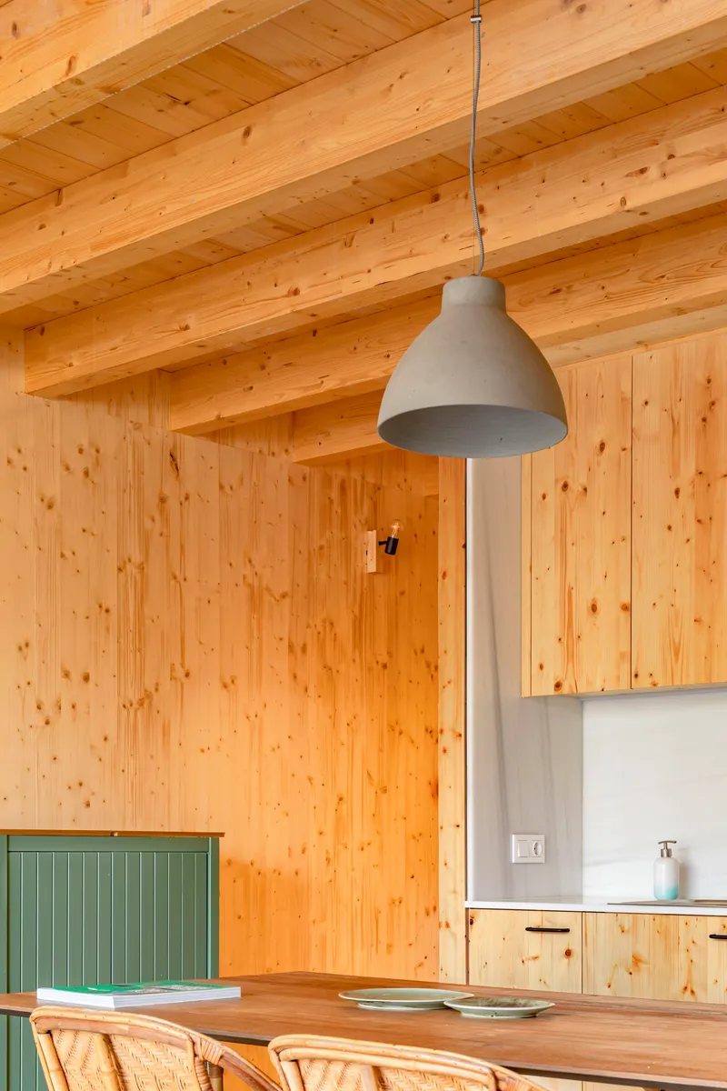 Kitchen interior with exposed timber beams and pendant light over a wooden dining table