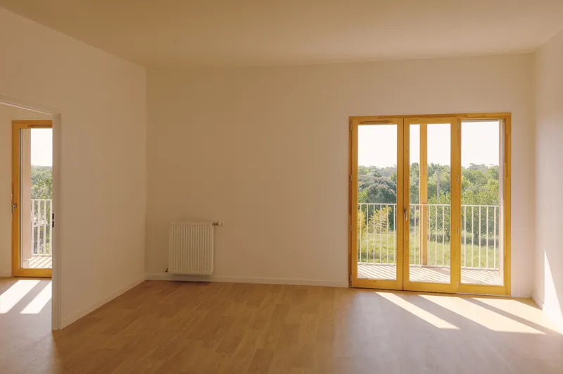 Interior room with light wood flooring, white walls, radiator, and timber-framed glass doors opening to a balcony