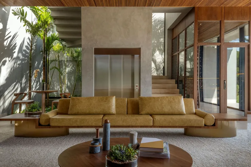 Interior courtyard with planted bed casting shadows on concrete wall beside an elevator