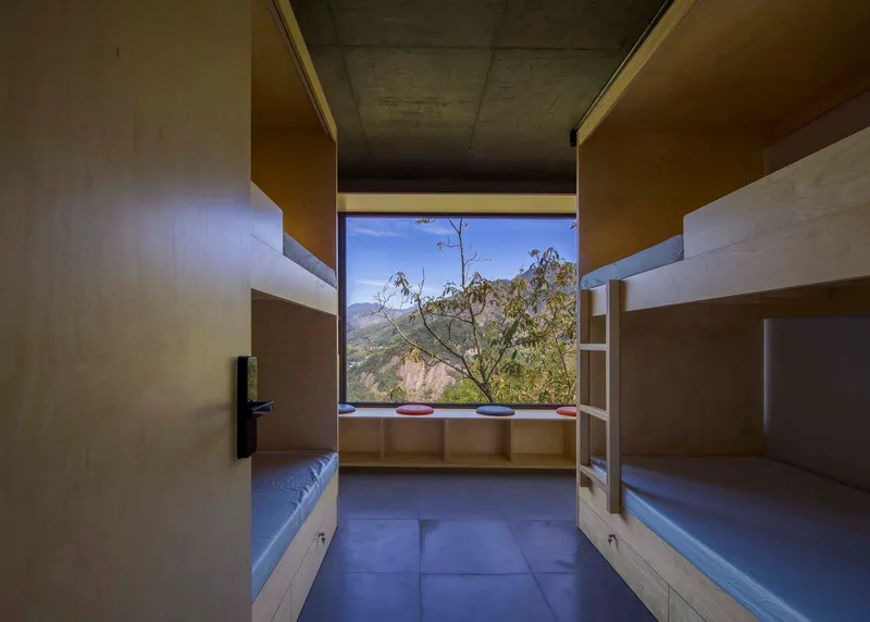 Dormitory room with built-in timber bunk beds and a window seat overlooking distant mountains