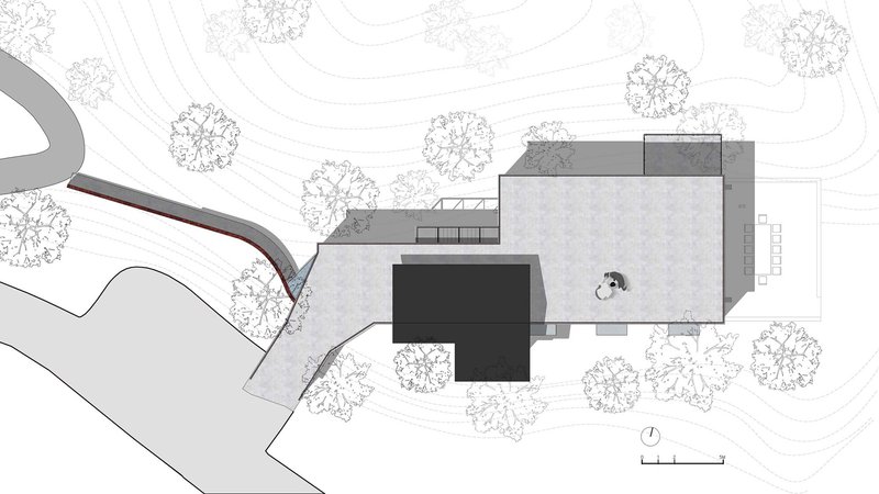 Site plan showing stepped volumes embedded into a sloped terrain with surrounding tree canopy