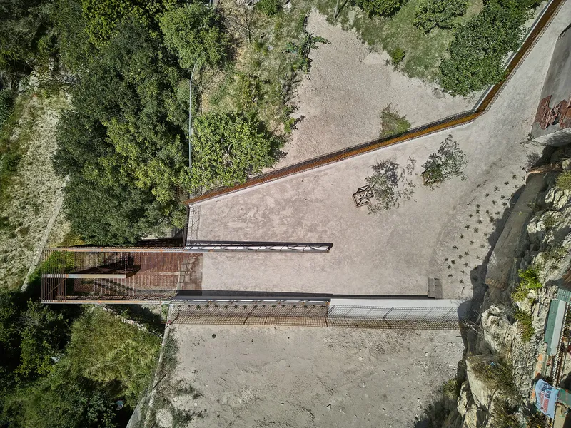 Aerial view of the concrete plaza with metal deck and railings adjacent to dense tree canopy