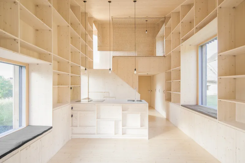 Interior view of plywood shelving walls and central kitchen island under a mesh mezzanine ceiling