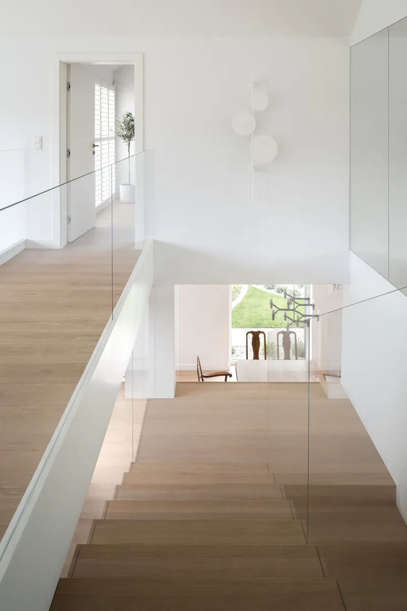 Upper level hallway overlooking the stairwell with glass balustrade and timber flooring