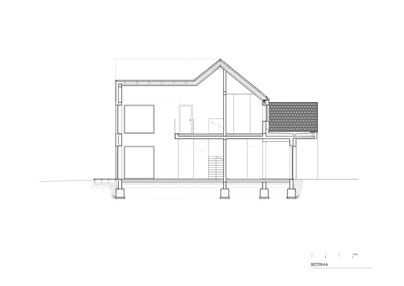Section drawing showing a two-story residence with angled roof and concrete pier foundations