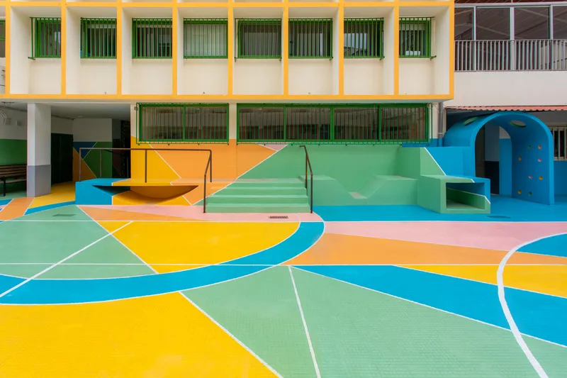Painted concrete steps and slide descending to the patterned courtyard under blue sky