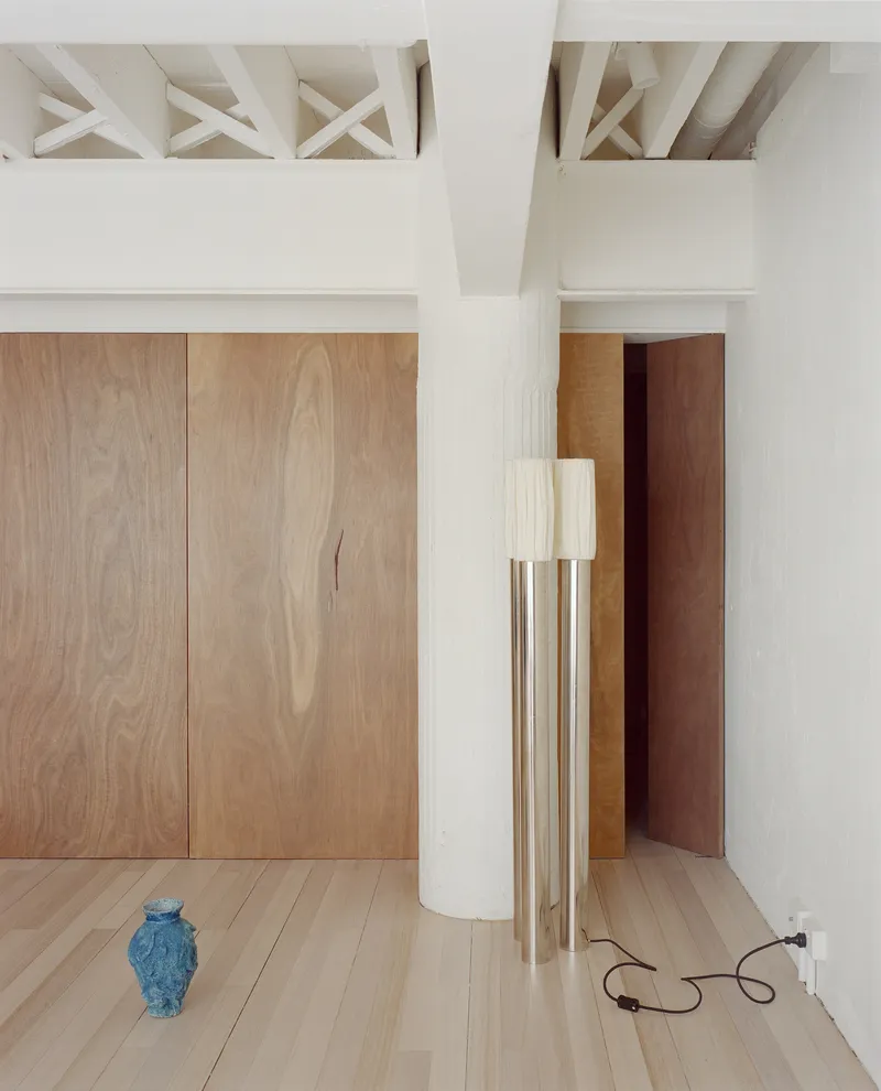 Room corner showing exposed timber ceiling structure, oak paneling, white column and blue ceramic vase