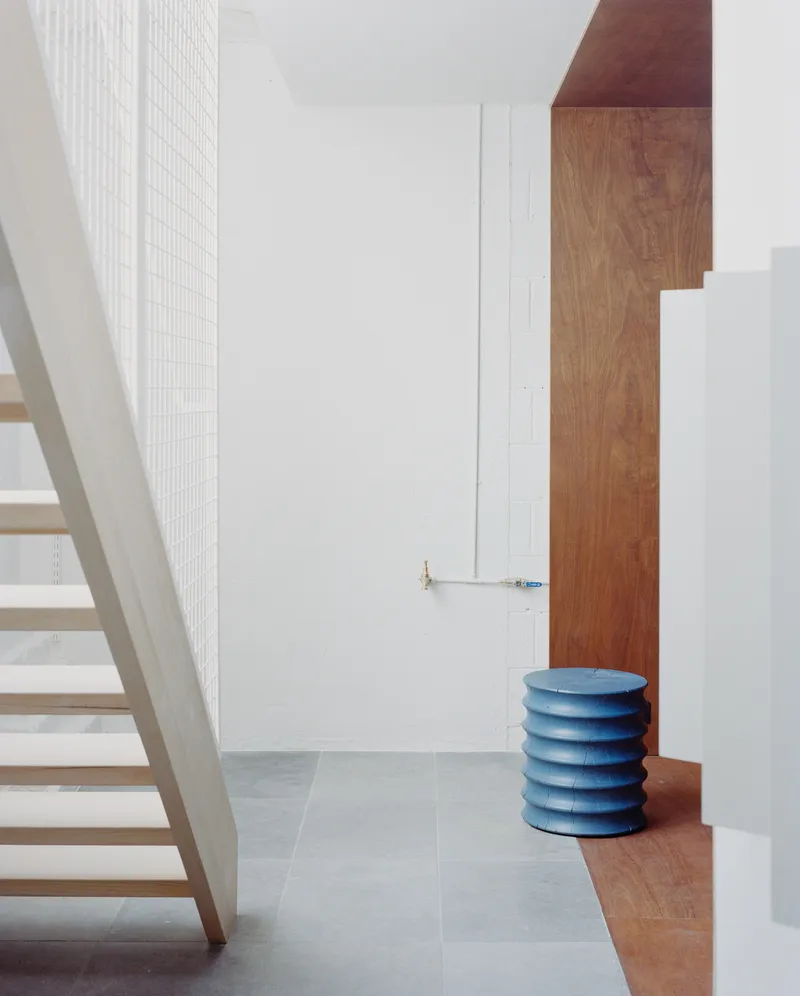 Stairwell view with timber treads, white mesh screen wall, oak paneling and blue stacked seat