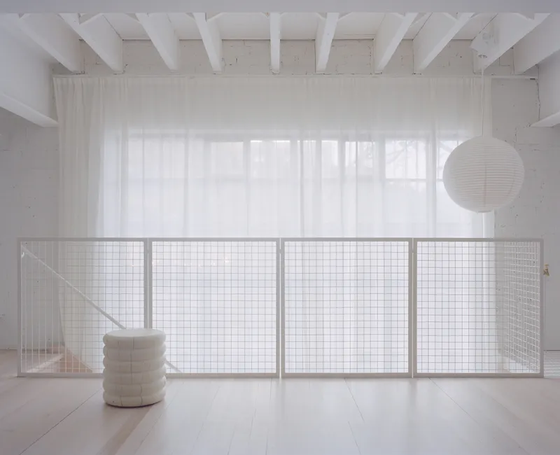 Interior mezzanine with wire mesh balustrade and white timber ceiling beams in diffused daylight