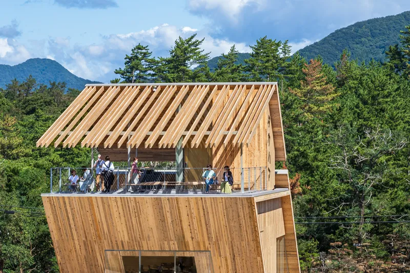 Upper viewing deck with slatted timber roof structure and glass railings framed by distant mountains