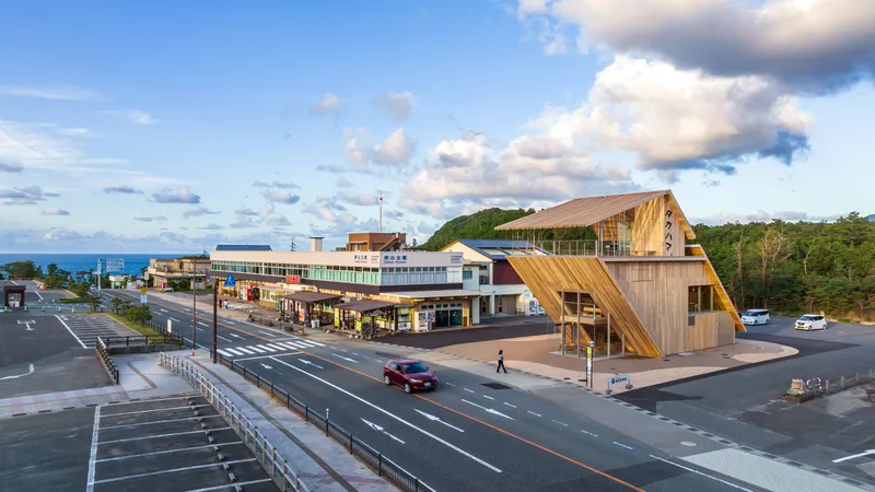 Elevated view of the timber pavilion and adjacent station buildings at dusk with passing traffic