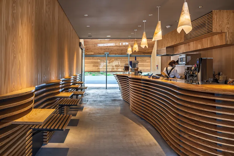 Interior cafe counter with horizontal slatted timber cladding and conical pendant lights overhead