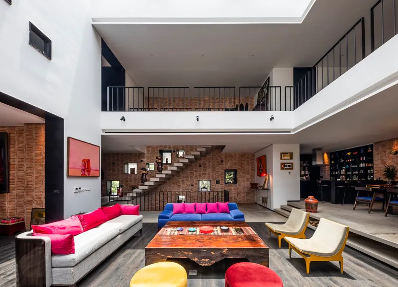 Central floating staircase anchored to exposed brick wall beneath a continuous upper-level gallery