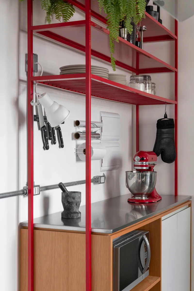 Red steel shelving frame in kitchen area with hanging knives and countertop mixer