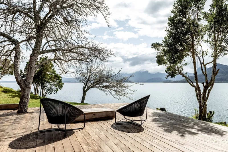 Timber deck with lounge chairs overlooking the lake and distant mountains under partly cloudy skies