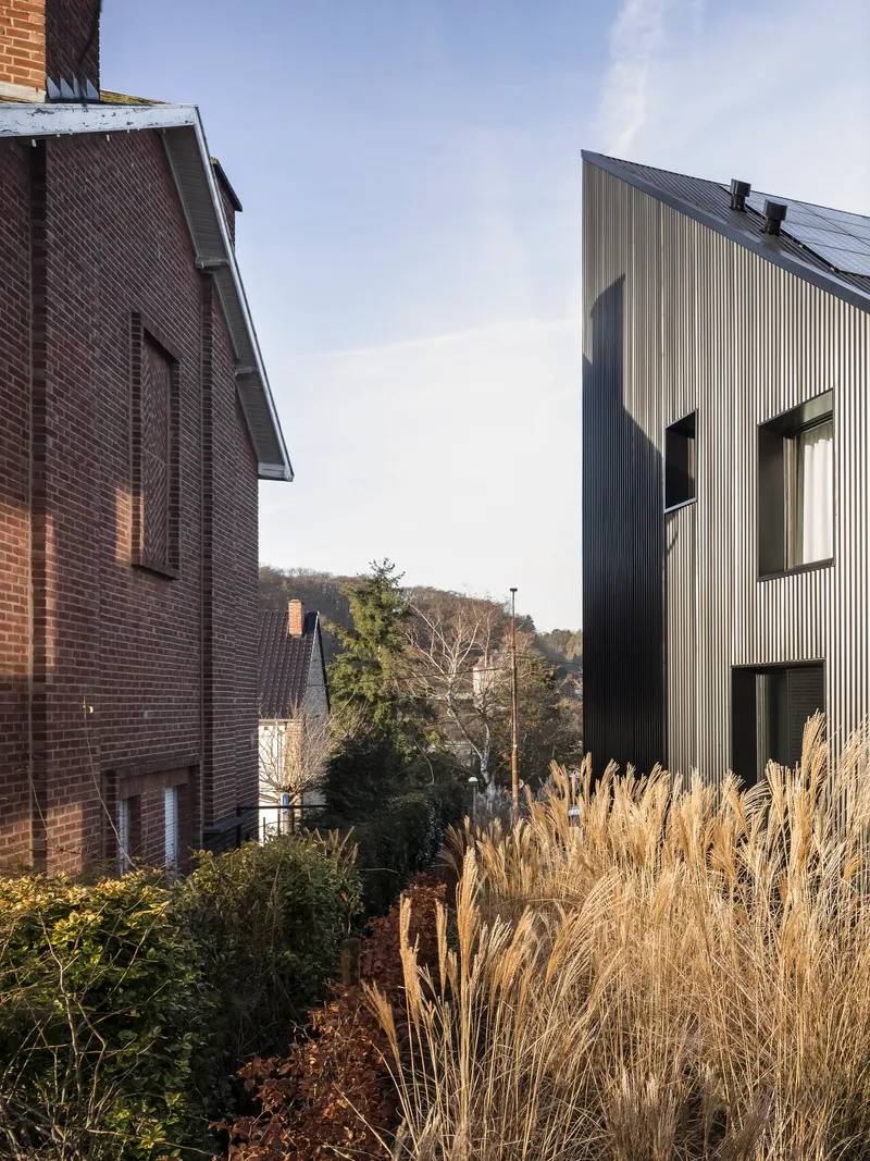 Rear view showing the vertical corrugated cladding beside a planted garden with ornamental grasses