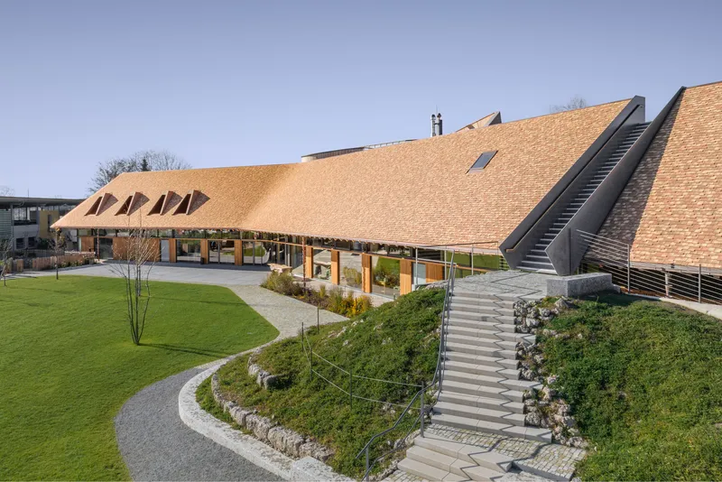 Landscaped courtyard with curved paths and wide steps leading to the shingled roof with dormers