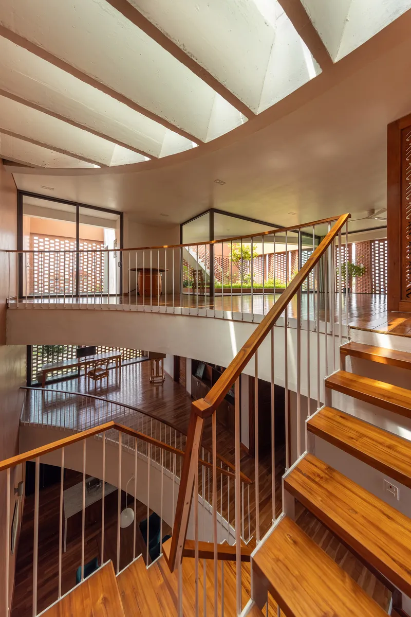 Multi-level staircase with timber treads and metal railings wrapping around an open courtyard void