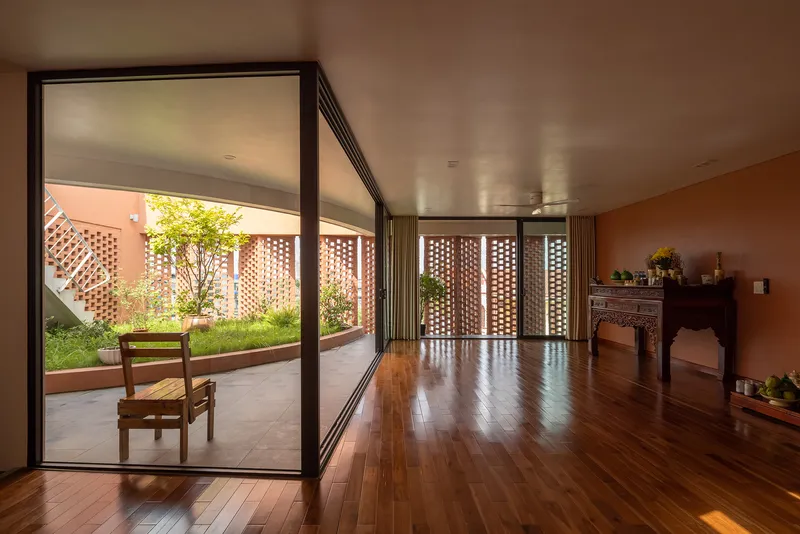 Interior living space with dark wood flooring opening to a small courtyard with lattice screen