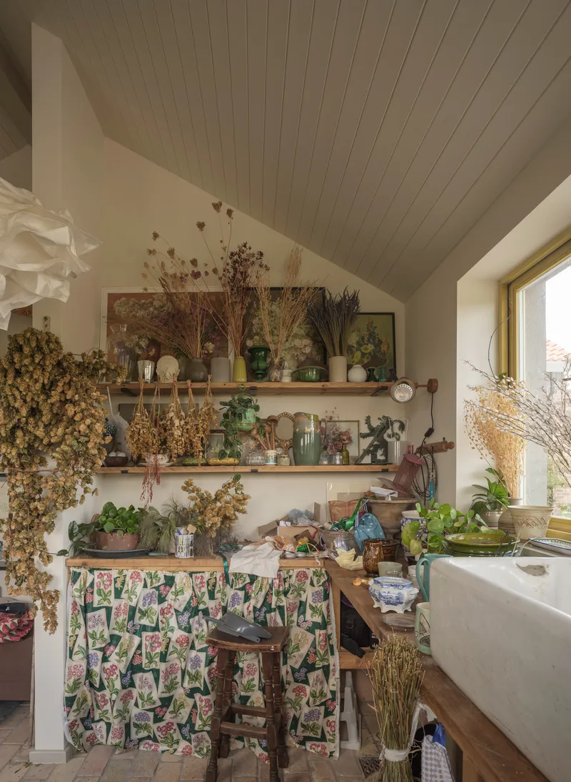 Kitchen corner with painted tongue-and-groove ceiling and open shelves displaying dried flowers and ceramic vessels