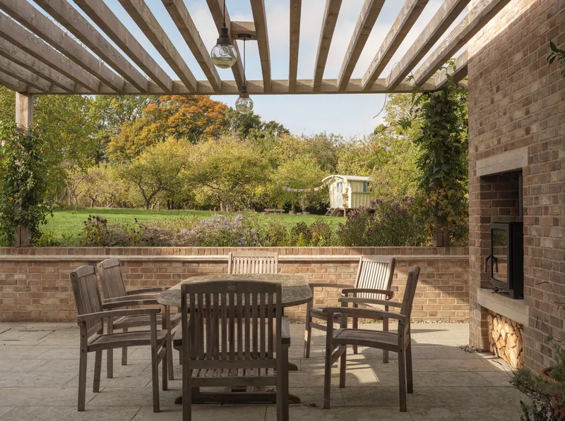 Covered terrace with timber pergola beams framing a view of the garden in autumn