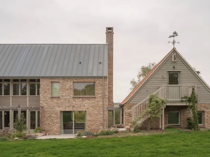 Garden elevation showing metal roof volumes and weather vane atop timber-clad gable with lawn foreground