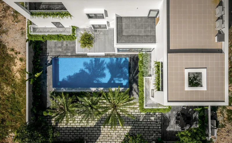 Aerial view showing the swimming pool surrounded by paved courtyard and planted terraces