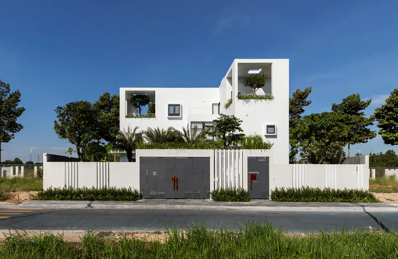 Street view of white facade with stacked planted terraces behind vertical slat boundary wall