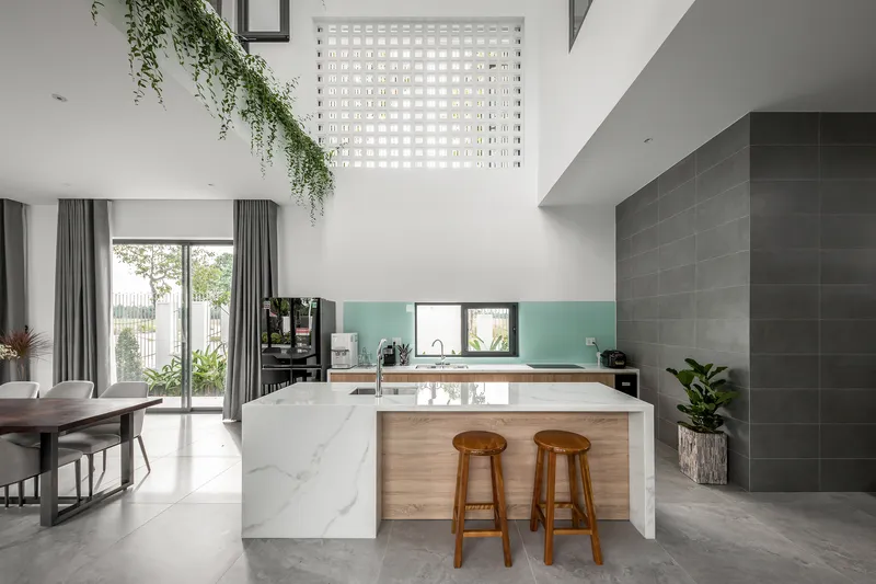 Open kitchen and dining area with marble island and perforated screen bringing daylight from above