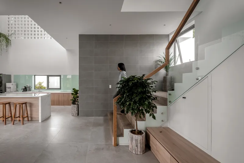 Grey tiled feature wall anchoring an open stairwell lit by a perforated skylight above