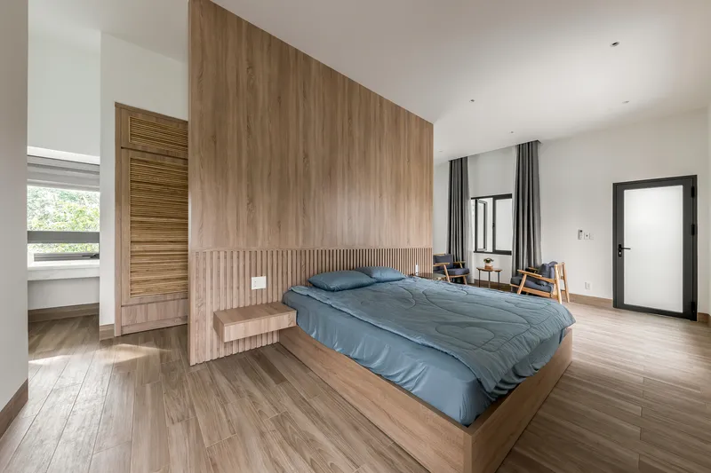Bedroom with vertical timber wall panels and integrated bedside ledge under soft overhead lighting
