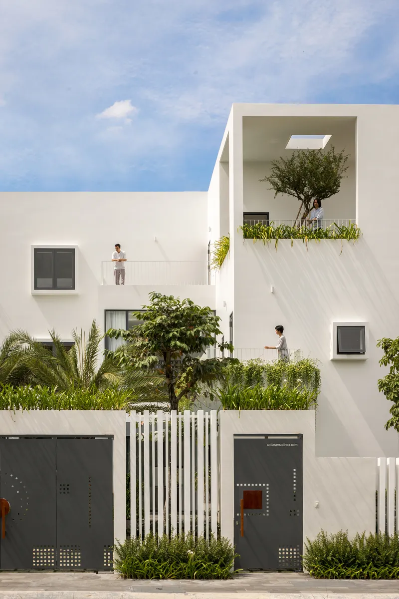 Street facade showing white volumes with recessed balconies and residents on upper terraces