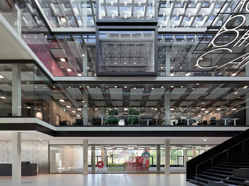 Glazed ceiling grid above stacked floor plates with planted greenery visible through the central opening