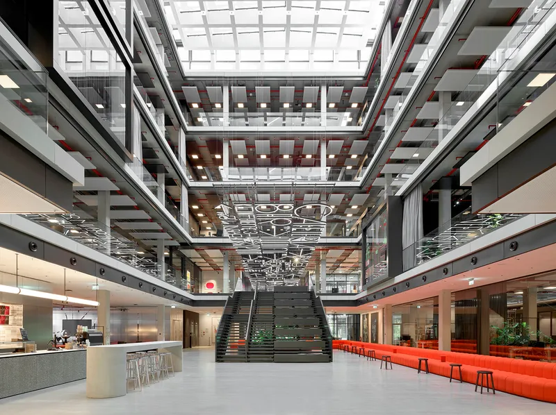 Interior atrium with central staircase, multilevel balconies, suspended light fixtures and glazed roof above