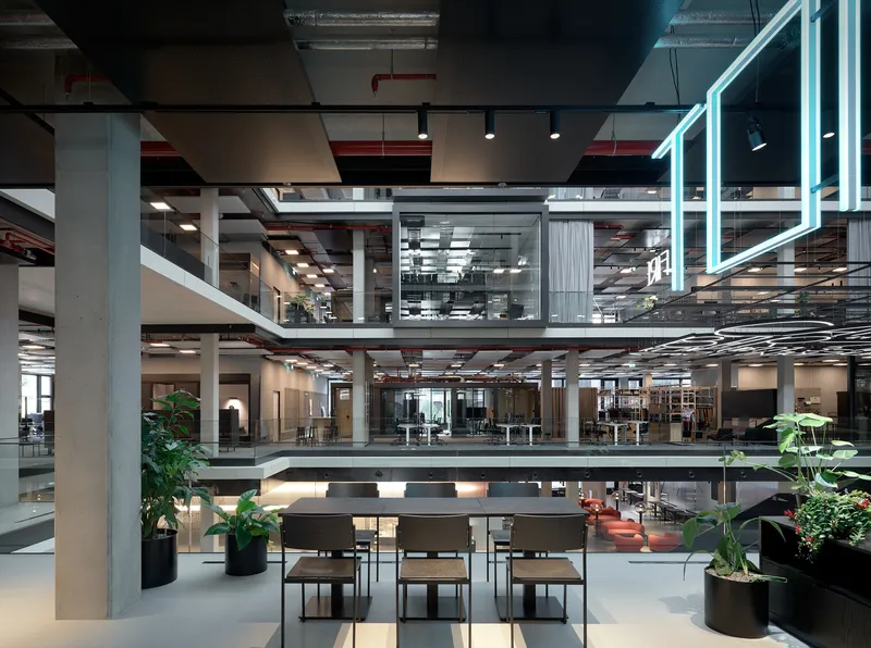 Ground floor seating area with planters looking up through exposed concrete columns and open work levels