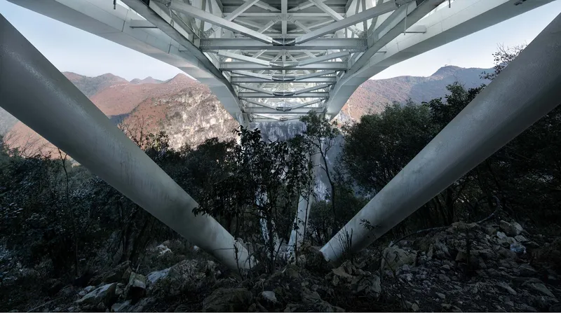 Underside view of the steel support columns and triangulated truss framework at dusk