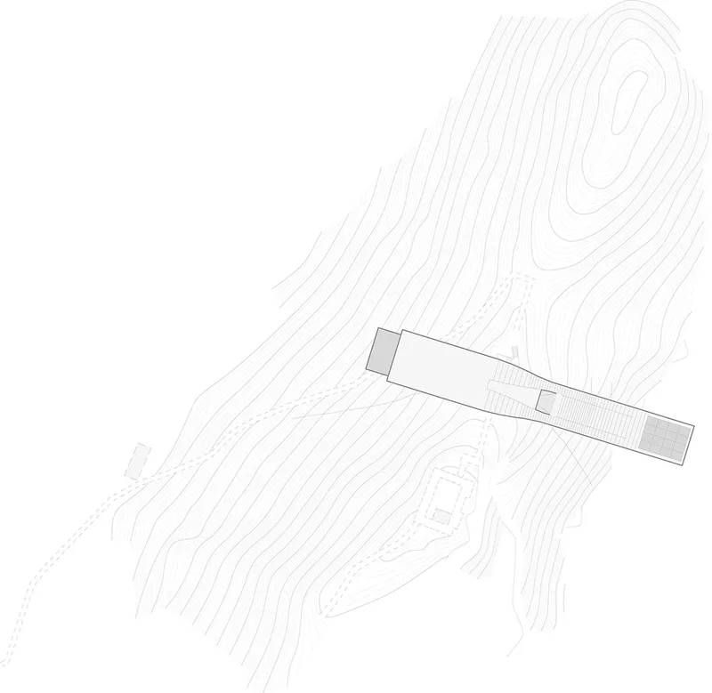 Site plan drawing showing a linear building positioned across contoured terrain with a rocky outcrop