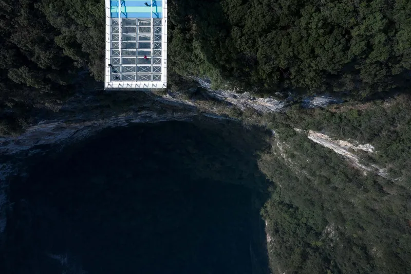 Overhead view of the rectangular glass roof structure at the cliff edge above dark water