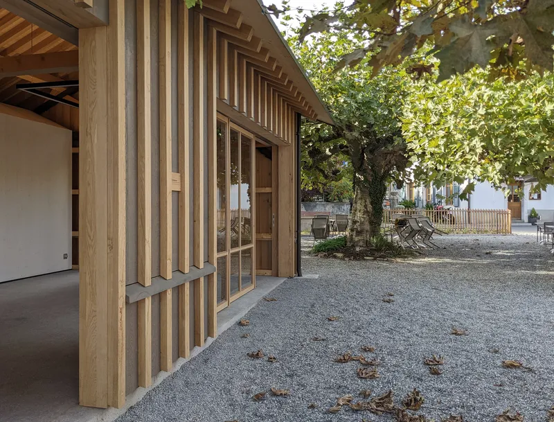 Glazed entrance set within vertical timber slat facade with overhanging eaves and adjacent trees