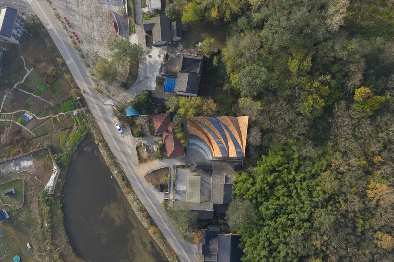 Overhead view showing the undulating timber roof forms adjacent to a canal and residential gardens