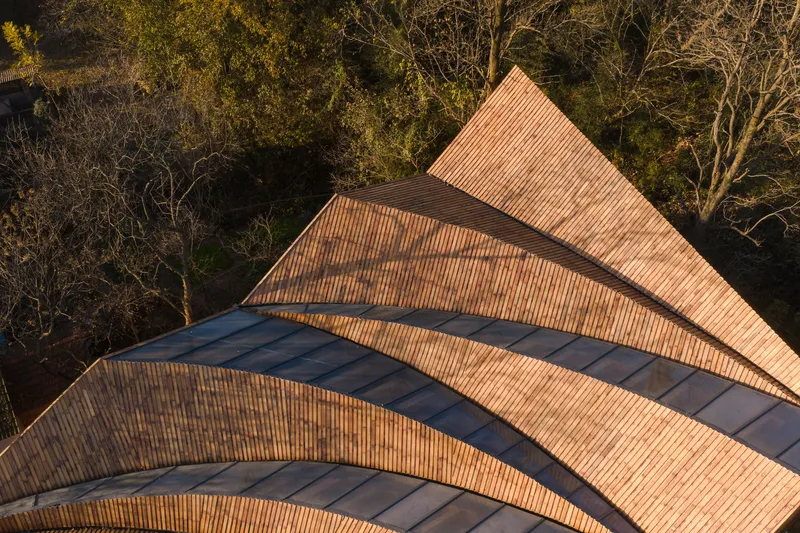 Aerial view of overlapping triangular roof planes clad in ribbed tile and dark metal flashing