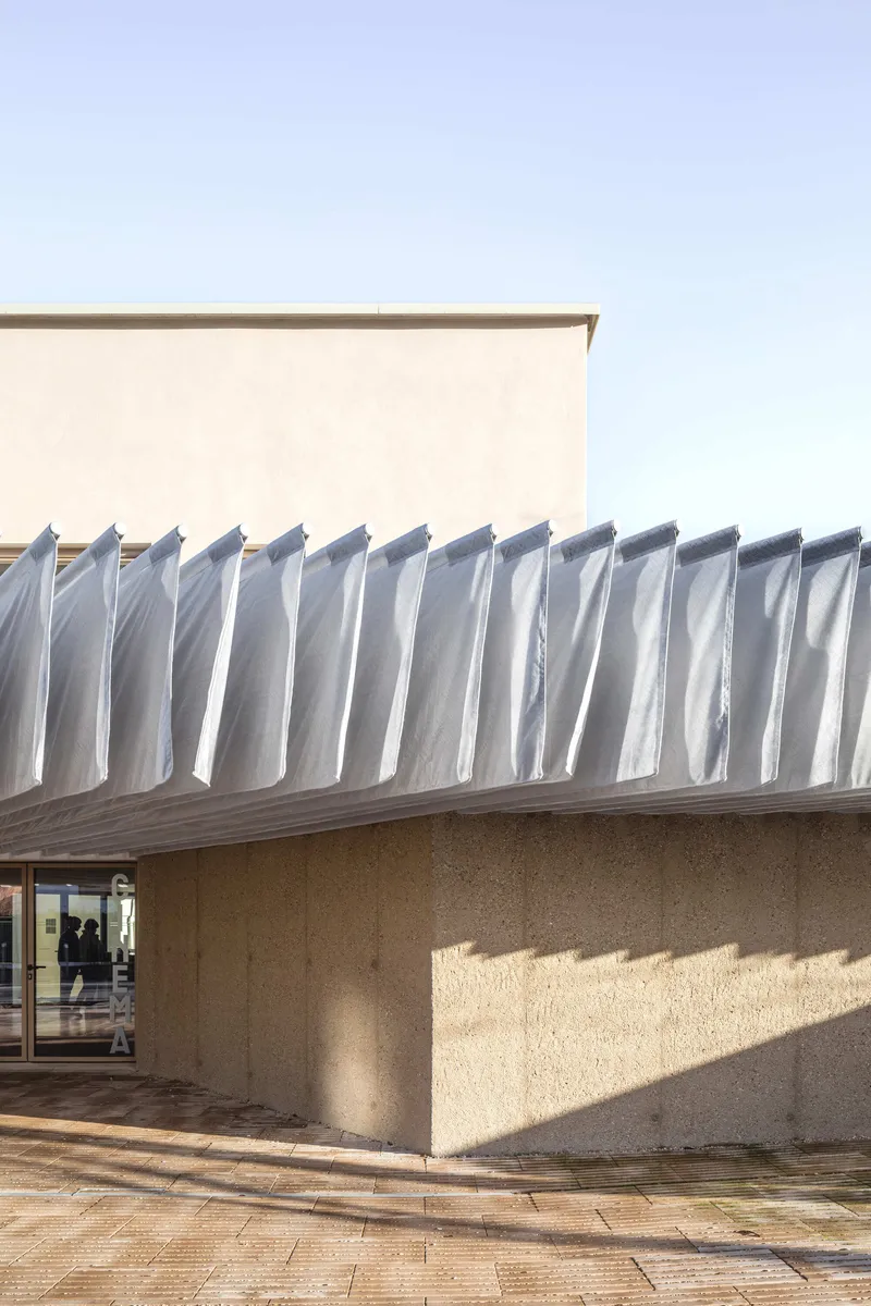 Close-up of the folded metal canopy above concrete walls casting sharp afternoon shadows