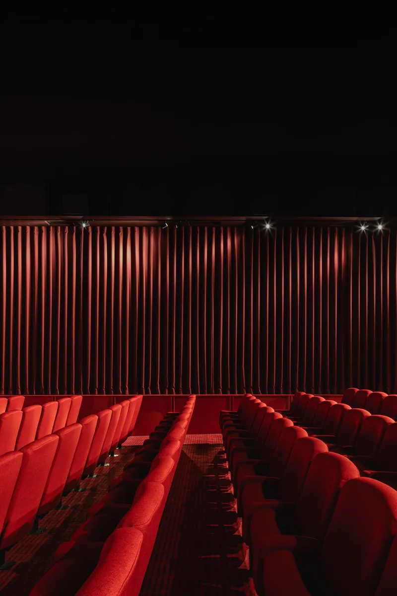Theater interior with rows of red velvet seats facing illuminated vertical wall panels