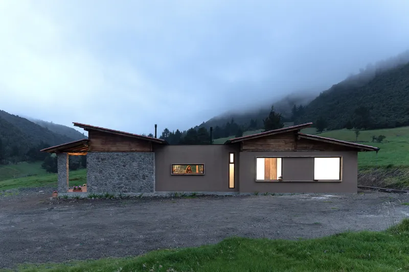Front facade with stone and rendered walls under angled timber roofs in misty valley light