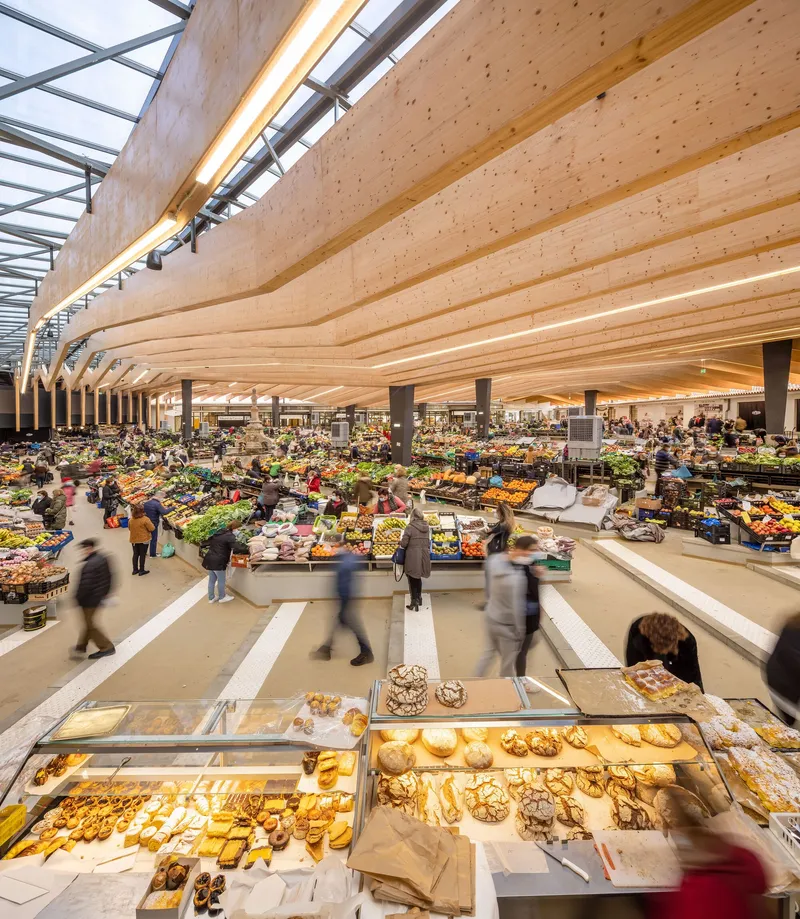 Interior view of the undulating laminated timber ceiling over the market hall with shoppers in motion